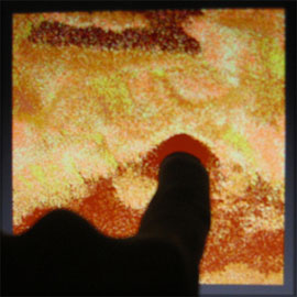 Sandbox sand dispersing under the touch of a finger